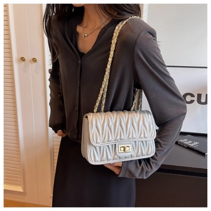 Detailed view of silver quilted matelasse bag with golden chain and metallic twist lock