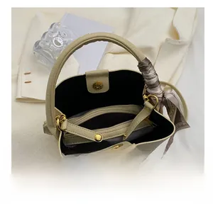 Detail view of cream-white bucket bag interior with zipper pocket and silk scarf accent