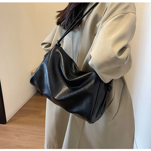 Detail of a large black PU leather Boston bag shown on model with soft lighting