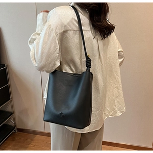 Detailed view of black lychee grain leather bucket bag with knotted shoulder strap detail