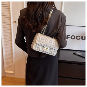 Silver quilted crossbody bag with gold chain strap shown on model's shoulder
