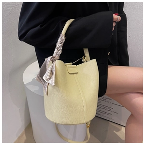 Detail of light yellow leather bucket bag with printed silk scarf on the top handle