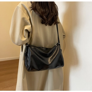 Detail of black leather Boston bag with decorative knots and beige trench coat styling