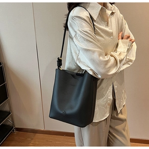 Close-up of black lychee grain leather bucket bag with unique knotted shoulder strap