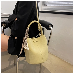 Detail of yellow lychee leather bucket bag with floral silk scarf and metal hardware