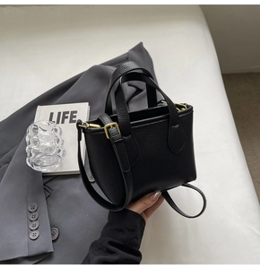 Close-up of black litchi grain leather handbag with gold hardware and fine stitching