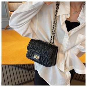 Detailed view of black quilted leather shoulder bag with golden metal chain strap