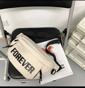 Detail of white cross-body bag featuring bold FOREVER letters and wide black strap