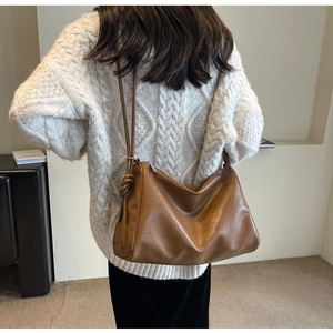 Close-up of brown textured leather Boston bag showing decorative strap knot detail