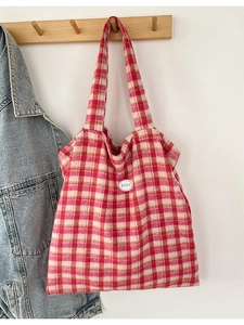 Red and white checkered tote bag with circular 'good' patch on a wooden wall hook