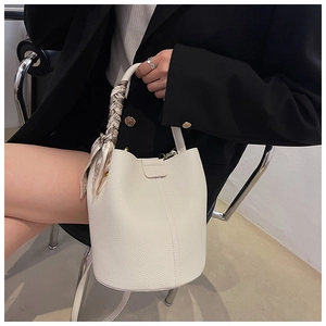 Chic cream bucket bag with silk scarf handle detail styled on a modern black blazer