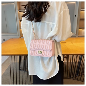 Detailed view of pink quilted chain bag with gold twist lock and woven leather strap