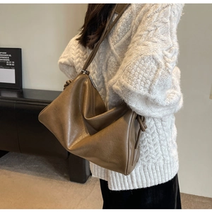 Detail view of brown leather Boston bag showing knot strap and metallic zipper closure