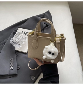 Detail of apricot mini crossbody bag with lychee grain texture and fuzzy monster charm