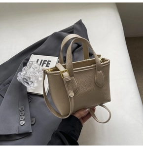 Detail of light beige lychee pattern leather handbag with gold metal hardware and strap