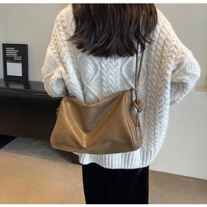 Dark brown leather hobo bag with knotted strap shown on model in white sweater