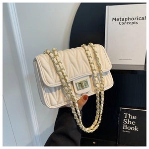 Close-up of quilted cream shoulder bag with gold V-stitch detail and turn-lock