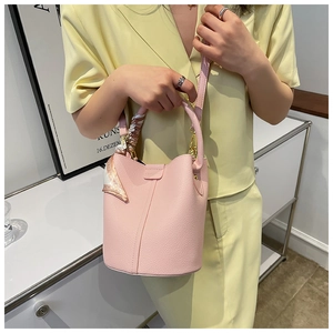 Detailed shot of pink pebble leather bucket bag with decorative patterned silk scarf handle