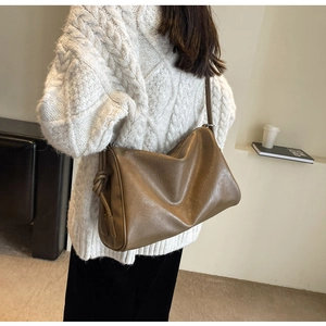 Detailed view of brown leather Boston bag with knot design and smooth texture