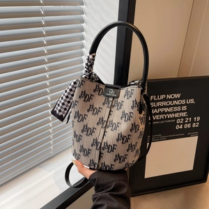 Detail der Bucket Bag mit Buchstabenprint, schickem Karoschal und schwarzem Ledergriff