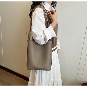 Detail of taupe pebbled leather bucket bag with knot shoulder strap and subtle logo