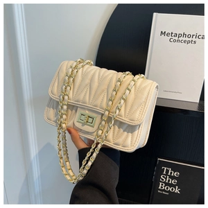 Detail of creamy white quilted crossbody bag with gold hardware and chain strap
