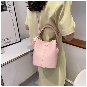 Detail of pink lychee grain bucket bag with decorative floral scarf and top handle
