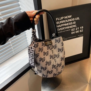 Detailansicht der Beuteltasche mit Buchstabendruck, Ledergriff und dekorativem Seidenschal