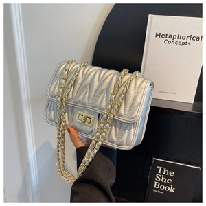 Detail of silver wavy matelassé quilted chain bag with gold metallic turn-lock closure