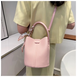 Detail of pink lychee leather bucket bag with printed silk scarf and crossbody strap