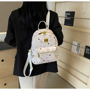 Detail eines weißen Mini-Rucksacks aus Leder mit Sternmuster und goldener Logo-Plakette