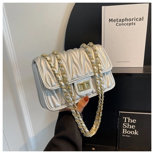 Detail of silver quilted chain bag with metallic finish and elegant gold twist lock