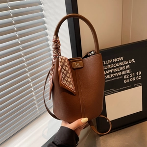 Detail der braunen Leder-Eimertasche mit kariertem Seidentuch und Metall-Markenlogo