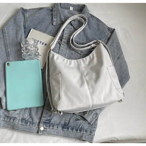 Detailopname van beige hobo-tas met zijzakken op een blauwe denim jas achtergrond