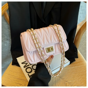 Close-up of pink quilted chain bag with V-stitch pattern and golden twist lock detail