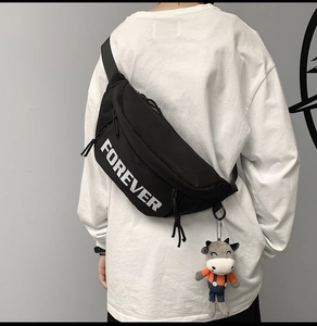 Close-up of black crossbody bag with white FOREVER print and cute plush calf pendant