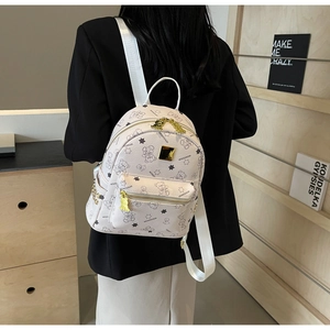 Nahaufnahme eines weißen Mini-Rucksacks mit Bärenmuster und Gold-Reißverschlüssen am Model