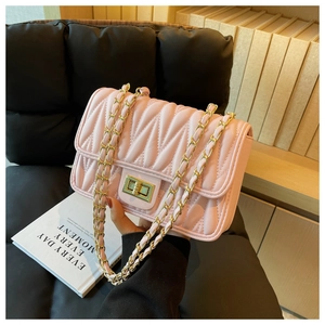 Detail of light pink quilted chain bag featuring wavy pleats and gold metal twist lock