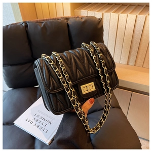 Detailed close-up of the gold twist lock and quilted leather pattern on the black crossbody bag