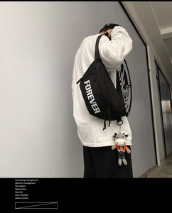 Close-up of black streetwear crossbody bag with white FOREVER text and a cute cow pendant