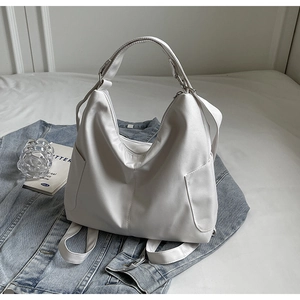 Detail van witte minimalistische hobo tas met matte afwerking en zilveren gespen