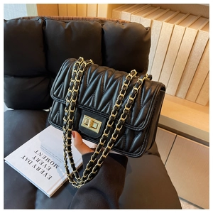Detail of black matelassé leather handbag with golden chain strap and twist lock closure