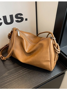 Caramel vintage Boston bag with knot strap detail on a dark wooden background