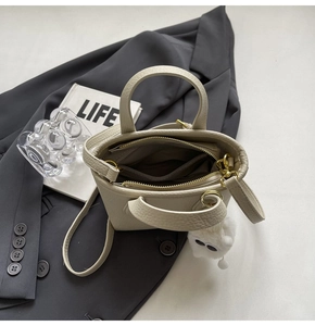 Detail view of cream textured mini bucket bag with interior zip pouch and monster charm