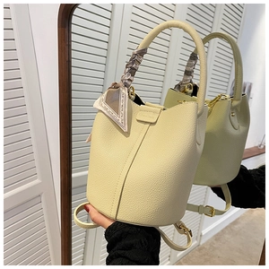 Detail of light yellow lychee leather bucket bag with printed silk scarf and crossbody strap