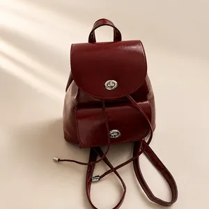 Detalle de mochila de cuero brillante burdeos con cierre de hebilla giratoria plata