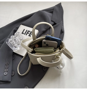 Close-up of beige bucket bag showing interior capacity for phone, wallet and lipstick