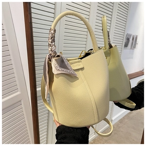 Close-up of cream lychee leather bucket bag with decorative silk scarf on handle