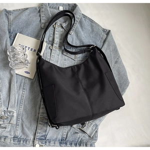 Minimalistische zwarte nylon hobo tas met zijvakken en een verstelbare schouderriem
