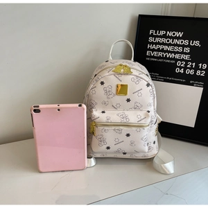 Detail eines cremefarbenen Rucksacks mit Bärenprint, Goldanhänger und iPad zum Vergleich